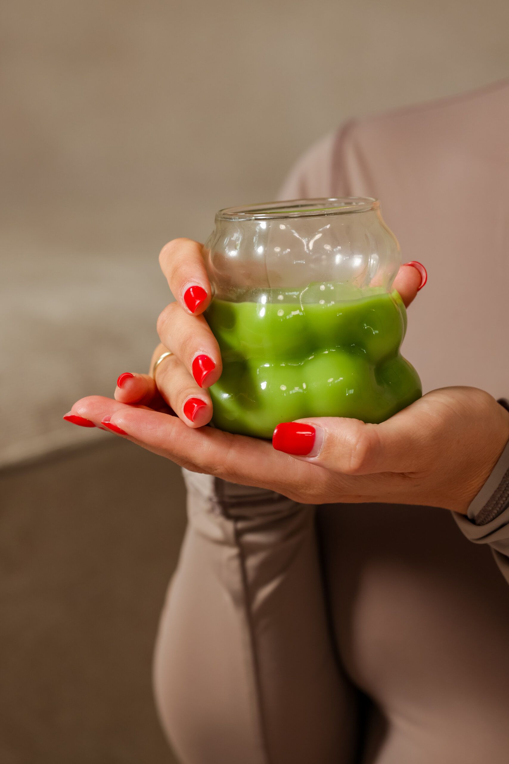 Een glas groene matcha in twee handen