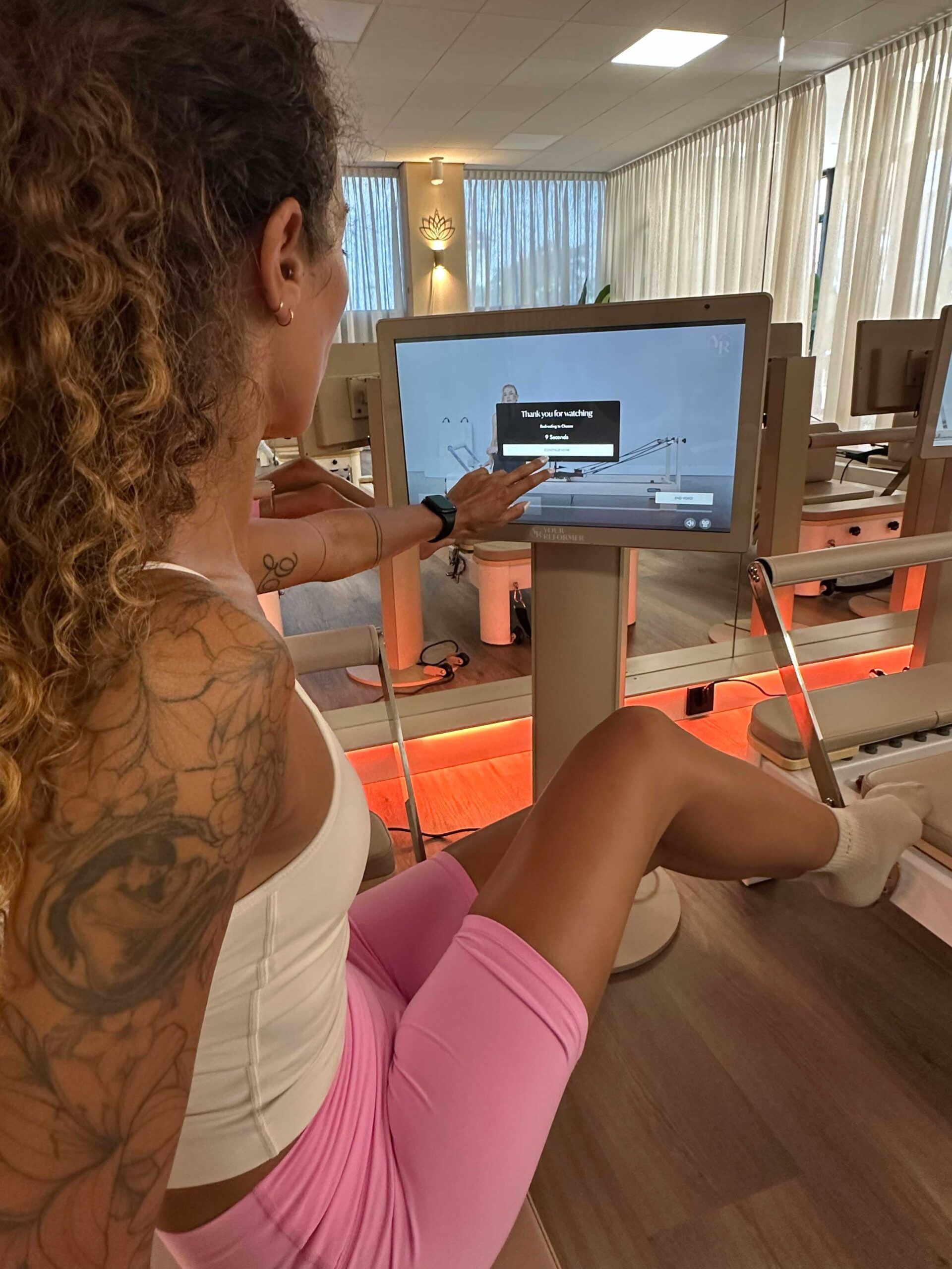 Een vrouw op de E-Reformer kiest haar training op het scherm